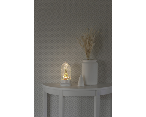 Dekorative Schneekugel mit Weihnachtsbaummotiv auf einem Tisch