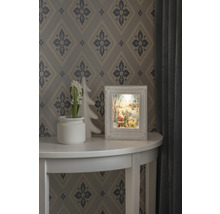 Dekorative Weihnachtsszene mit beleuchtetem Rahmen auf einem Tisch