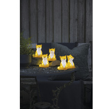 Dekorative Fuchsfiguren auf einem Gartentisch mit Pflanze und Kissen