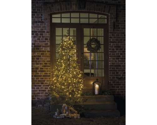 Dekorierte Eingangstür mit beleuchtetem Weihnachtsbaum, Adventskranz und Laterne für weihnachtliche Atmosphäre