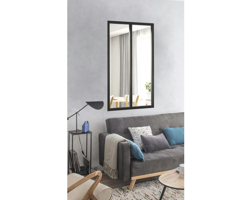 Wohnzimmer mit Sofa, Tisch und einem rechteckigen Spiegel mit schwarzem Rahmen