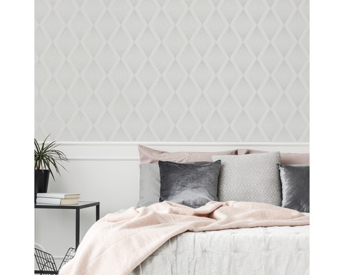 Schlafzimmer mit gemusterter Tapete im Diamantdesign, Bett und Nachttisch