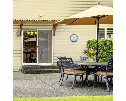 Terrassenszene mit Tisch, Stühlen, Sonnenschirm und Uhr an der Wand