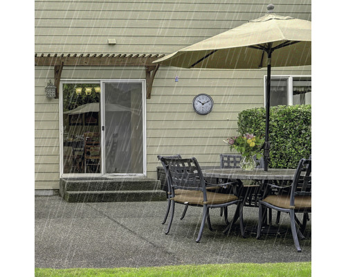 Gartenszene mit Terrassenmöbeln, Sonnenschirm und Regen