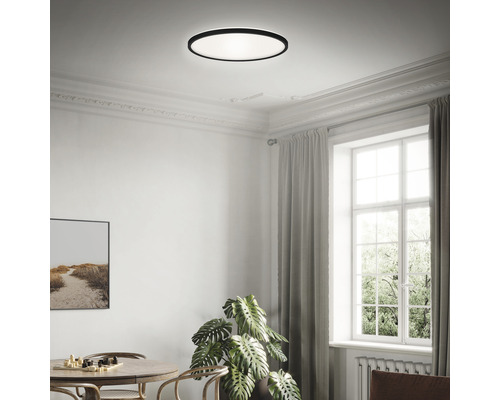 Ein heller Raum mit einer runden Deckenleuchte, einem Tisch und einem Fenster.