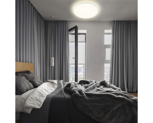 Schlafzimmer mit Bett, Vorhängen und runder Deckenleuchte