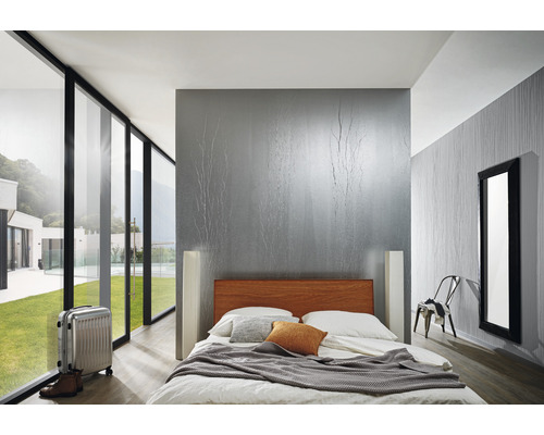 Helles Schlafzimmer mit Bett, Koffer und großem Fenster mit Blick ins Grüne