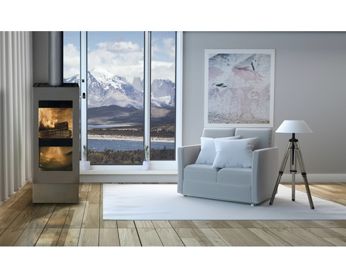 Wohnzimmer mit Kaminofen, Sofa und Lampe vor einem Fenster mit Bergblick