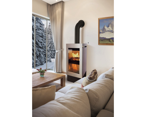 Wohnzimmer mit Kaminofen, Sofa, Holztisch und Fenster mit Winterlandschaft