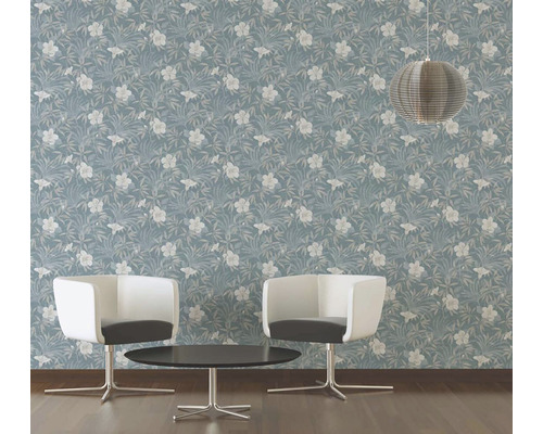 Ein Raum mit einer blauen Tapete mit Blumenmuster, zwei Stühlen und einem Tisch.