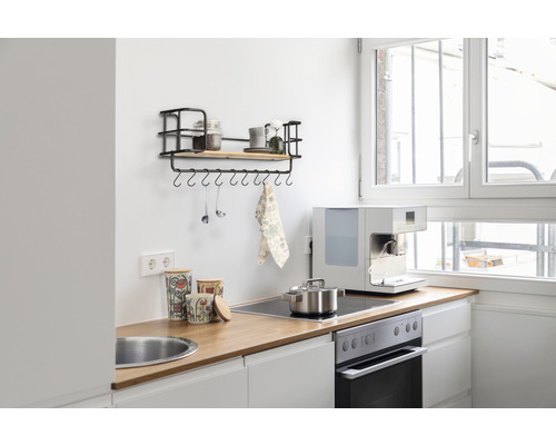 Küchenszene mit Hängeregal, Gewürzgläsern, Kochutensilien, Kochtopf, Kaffeemaschine und Vorratsdosen auf einer Arbeitsplatte