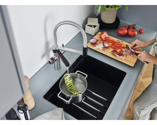 Küche mit Spüle, Armatur und Person beim Gemüseschneiden