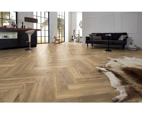 Heller Wohnraum mit Laminatboden im Fischgrätmuster, Sofa und Küchenbereich