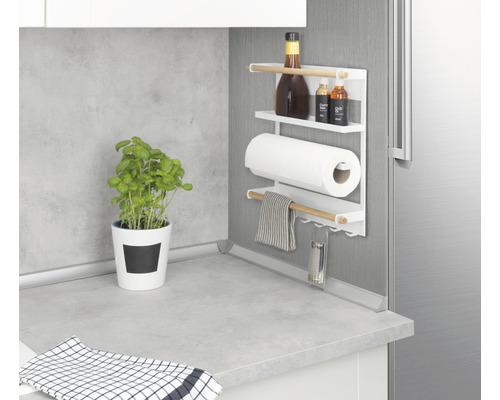 Küchenszene mit magnetischem Küchenrollenhalter mit Gewürzen, Küchenrolle, Geschirrtuch und Reibe an einer Kühlschranktür