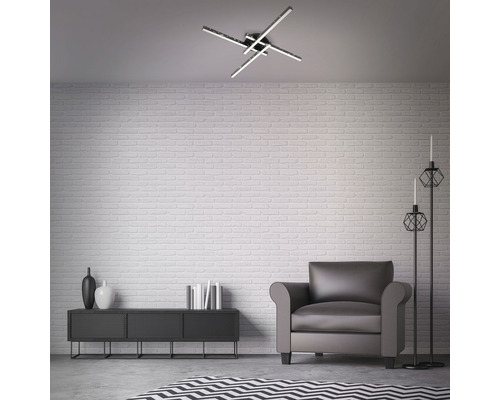 Modern eingerichtetes Wohnzimmer mit Deckenleuchte, Sessel, Schrank und Dekoration