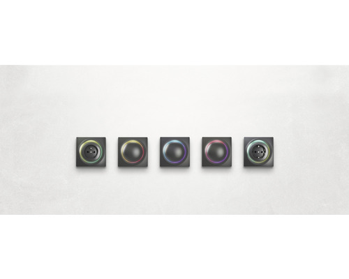 Fünf Schalter und Steckdosen mit farbiger Beleuchtung nebeneinander an einer Wand