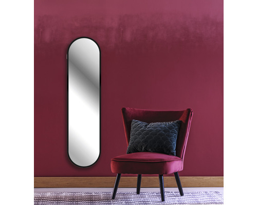 Einrichtungsbeispiel: Ovaler Spiegel, Sessel und Kissen vor einer Wand