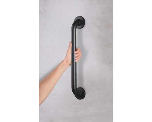 Schwarzer Haltegriff wird von einer Hand gehalten, zur Unterstützung und Sicherheit im Bad