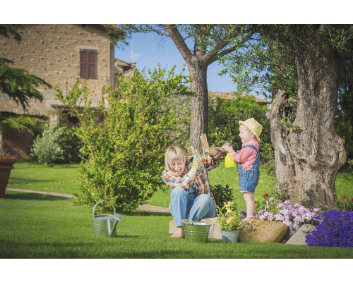 Szene im Garten mit Frau und Kind beim Gießen der Pflanzen mit einer Sprühflasche.
