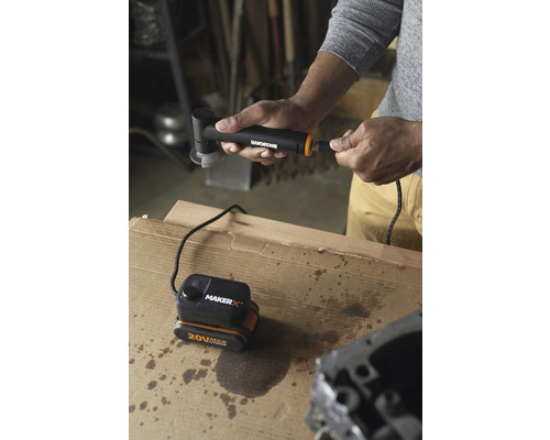 Eine Person verbindet einen Akku-Winkelschleifer mit einer 20-Volt-Batterie auf einer Werkbank.