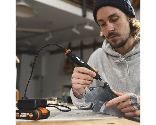 Ein Mann verwendet ein WORX Multifunktionswerkzeug mit Akku und Flexwelle, um ein Werkstück zu bearbeiten.