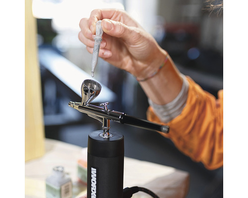 Person befüllt Airbrushpistole mit Pipette