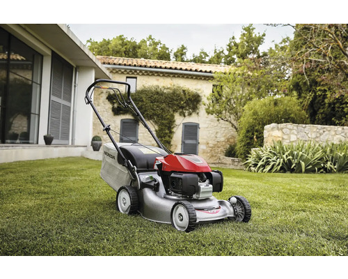 Rasentrimmer auf Rasen vor Haus und Garten