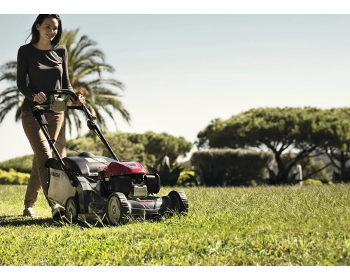 Frau bedient Rasenmäher im Garten