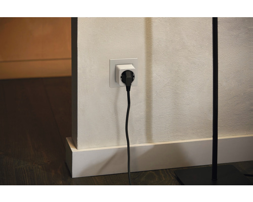 Steckdosenadapter mit eingestecktem Stecker an einer Wand