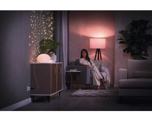 Wohnzimmer mit Beleuchtung, Kommode, Sofa und Frau