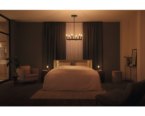 Schlafzimmer mit Bett, Nachttischen, Stuhl, Sessel, Deckenleuchte und Dekoration