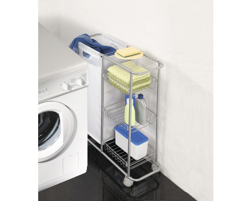 Wäschewagen mit Wäschekorb, Handtüchern und Reinigungsmitteln neben einer Waschmaschine.