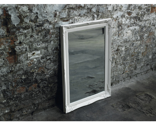 Rechteckiger Spiegel mit verziertem Rahmen lehnt an einer Wand