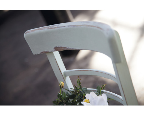 Detailansicht der Rückenlehne eines Holzstuhls mit Blumendekoration