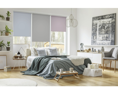 Schlafzimmer mit Bett, Kommode und Fenstern mit Rollos in verschiedenen Farben.