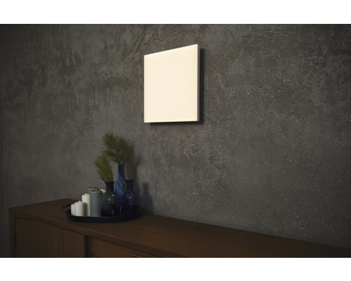 Quadratische Wandheizung über Holzkommode mit Dekoration an strukturierter Wand