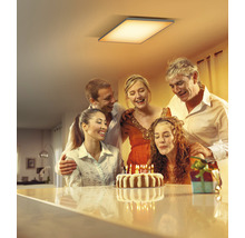 Szene mit einer Familie, die eine Geburtstagstorte unter einer Deckenleuchte feiert.