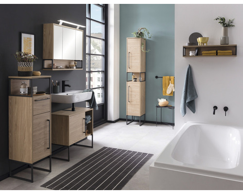 Badezimmer mit Waschtisch, Spiegelschrank, Hochschrank und Badewanne in hellem Holzdekor und schwarzem Metallgestell.
