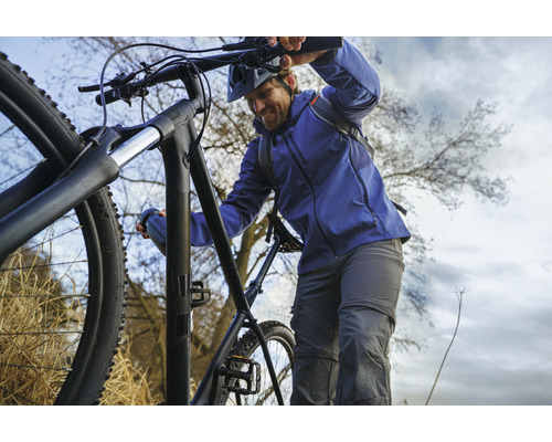 Mann schiebt ein schwarzes Mountainbike bergauf