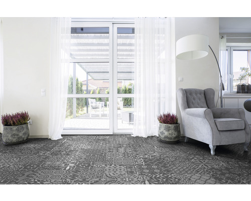 Wohnzimmer mit gemustertem Vinylboden, Sessel und Topfpflanzen vor einer Terrassentür