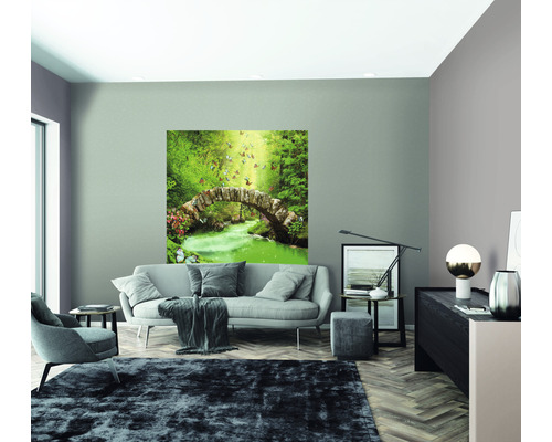 Wohnzimmer mit Sofa, Sessel, Teppich und einem Wandbild mit einer Steinbrücke in einem Wald