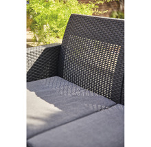 Nahaufnahme eines schwarzen Rattansofas mit Sitzkissen im Garten