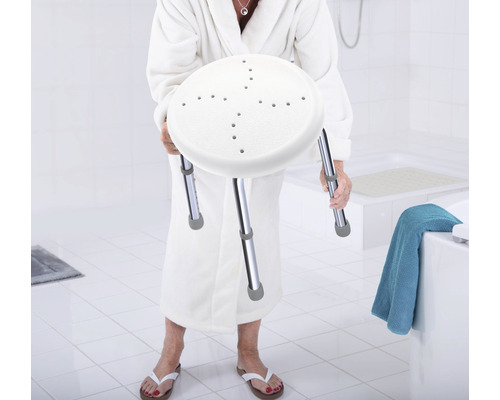 Frau im Bademantel hält Duschhocker mit höhenverstellbaren Beinen