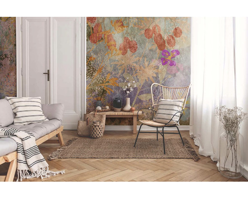 Wohnzimmer mit Sofa, Stuhl und Wandtapete mit Pflanzenmotiven für eine helle Atmosphäre.