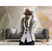 Wohnzimmer mit geometrischer Tapete, grauer Couch und einem Mann mit Hut
