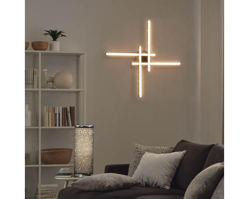 Wohnzimmer mit beleuchteter Wandlampe, Stehlampe, Regal und Sofa.