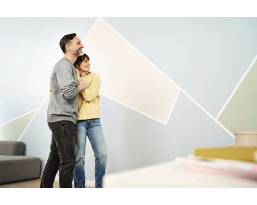 Ein Paar umarmt sich vor einer Wand mit geometrischen Formen