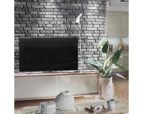 Wohnzimmer mit gemauerter Akzentwand, Fernseher, Stehlampe und dekorativen Elementen auf einem Couchtisch