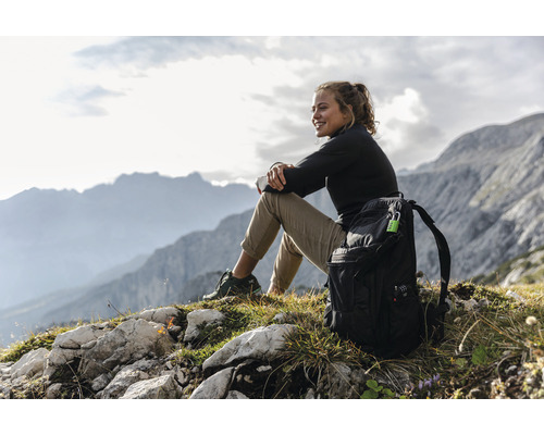 Frau sitzt mit Rucksack in den Bergen und genießt die Aussicht