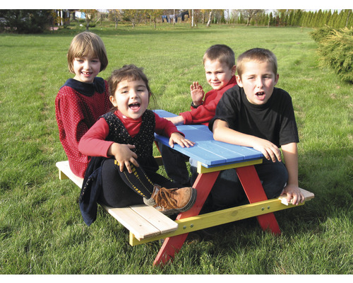 Vier Kinder sitzen an einem Picknicktisch im Garten.